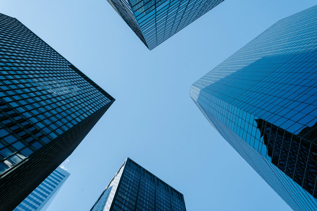 pexels-photo-7078666-7078666 Low angle of high business towers with glass mirrored windows located in megalopolis downtown against blue sky